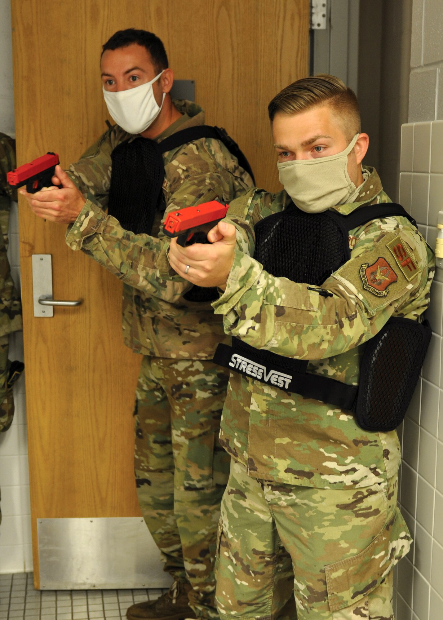Staff Sgt. Johnathan Rogers, front, and Staff Sgt. Luke Gehring, 445th Security Forces Squadron, engage a target in a locker room during a use of force training on July 12, 2020. The training, designed to closely mirror real-world scenarios, incorporated vests which deliver a minor electric shock to the wearer if another participant makes positive contact with a simulated firearm. (U.S. Air Force photo/1st Lt. Rachel Ingram)