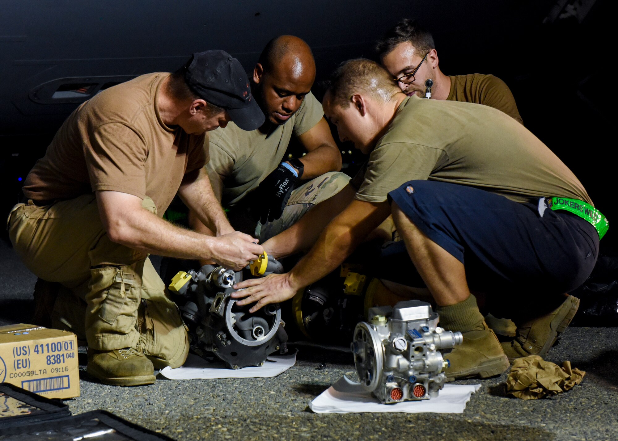 Airmen from the 5th Expeditionary Air Mobility Squadron and members of the Canadian 429 Squadron prepare a fuel pump for installation.