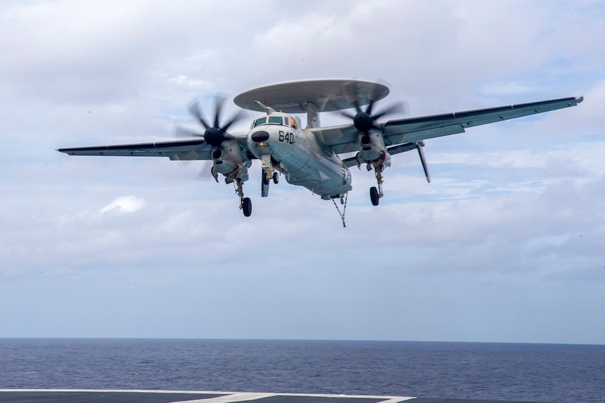 An E-2D Tracer, attached to the "Greyhawks" of Airborne Command and Control Squadron (VAW) 120, approaches the  flight deck of the aircraft carrier USS Gerald R. Ford (CVN 78).