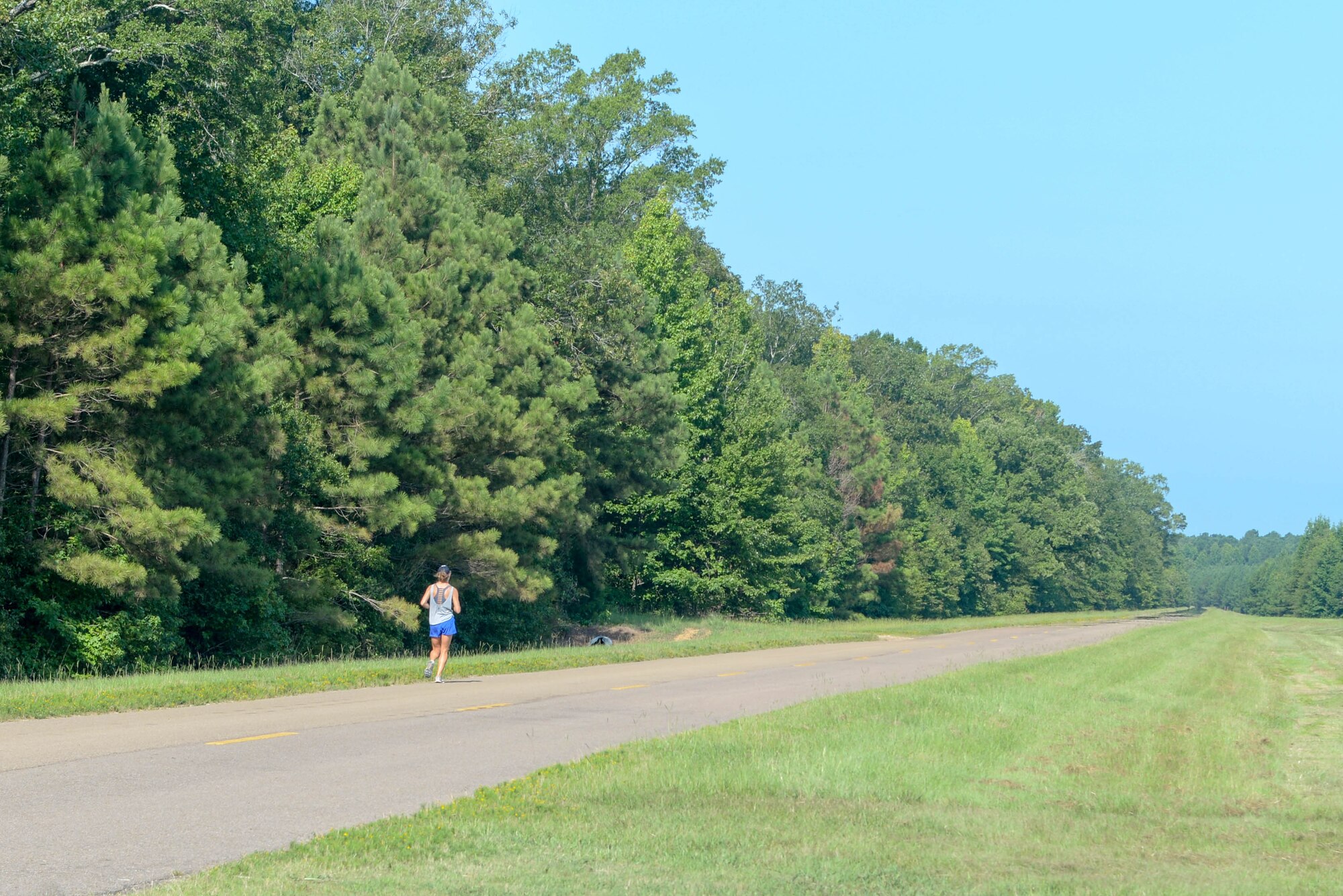 A person runs on Perimeter Road on August 5, 2020, at Columbus Air Force Base, Miss. For a more fun and less strenuous form of exercise, Floyd said members should use the fitness center’s tennis and basketball courts, and the Frisbee golf course across from the fitness center. (U.S. Air Force photo by Airman 1st Class Davis Donaldson)