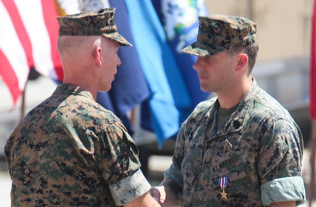 A Marine Raider was awarded the Silver Star Medal for heroic actions while deployed to Afghanistan in 2019, at a ceremony aboard Marine Corps Base Camp Lejeune. July 10, 2020. The master sergeant and Critical Skills Operator, was serving as a Team Chief with 2nd Marine Raider Battalion in support of Operation Freedom’s Sentinel when his team was engaged by enemy combatants. According to the award citation, during a heliborne raid into difficult enemy-controlled terrain in Southern Afghanistan, he led his team of Marine Raiders and partner nation forces in four hours of close combat with more than a dozen Taliban fighters occupying defensive strongholds.  The Team Chief exposed himself to enemy fire to lead an assault across 30 meters of open terrain, attacking Taliban fighters entrenched in a bunker with his rifle and hand grenades. While he and his team took accurate enemy fire, the Team Chief again exposed himself by climbing on top a building to employ a roof charge in order to recover a wounded Afghan soldier. With enemy fighters barricaded just a few feet away, he heroically pulled the wounded man to a covered position in a valiant attempt to save his life, while allowing his team to engage the barricaded fighters with fragmentation grenades.