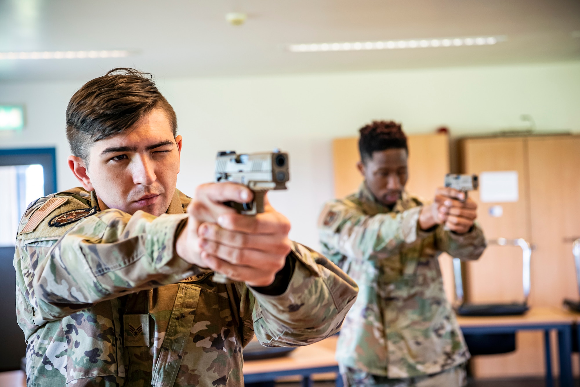 U.S. Air Force Senior Airman Michael Pritchard, left, 423rd Security Forces Squadron (SFS) patrolman, looks down the sight of an M18 handgun during a qualification course at RAF Molesworth, England, July 28, 2020. During the course, Airmen from the 423rd SFS became familiar with the M18 and learned about its various functions and overall benefits such as improved ergonomics, target acquisition, reliability and durability to increase shooter lethality. The M18 Sig Sauer Modular Handgun System will be replacing the M9 Beretta which has been in use for over 30 years. (U.S. Air Force photo by Senior Airman Eugene Oliver)