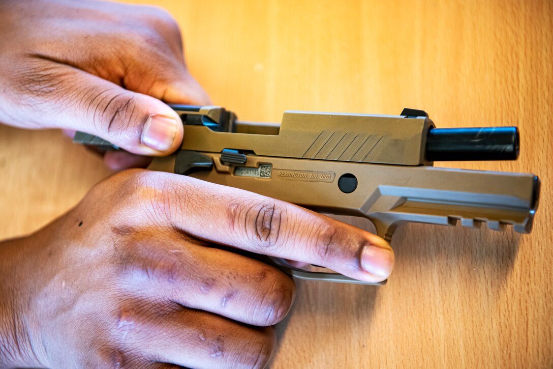 An U.S. Air Force Airman from the 423rd Security Forces Squadron (SFS), disassembles an M18 handgun during a qualification course at RAF Molesworth, England, July 28, 2020. The M18 Sig Sauer Modular Handgun System will be replacing the M9 Beretta which has been in use for over 30 years. During the course, Airmen from the 423rd SFS became familiar with the M18 and learned about its various functions and overall benefits such as improved ergonomics, target acquisition, reliability and durability to increase shooter lethality.  (U.S. Air Force photo by Senior Airman Eugene Oliver)