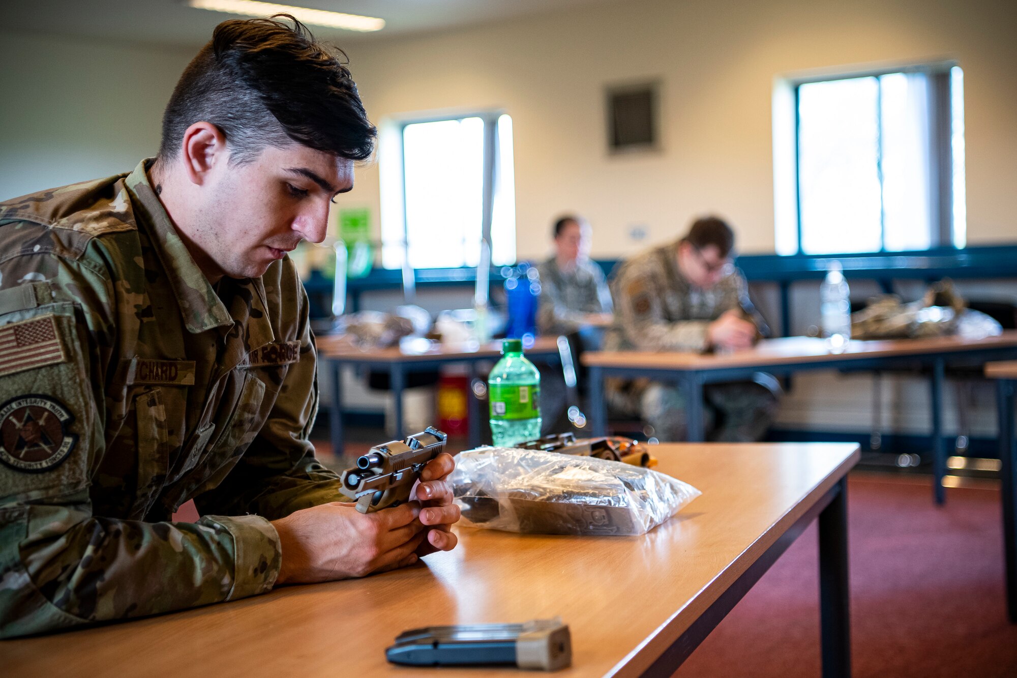 U.S. Air Force Senior Airman Michael Pritchard, left, 423rd Security Forces Squadron (SFS) patrolman, inspects an M18 handgun during a qualification course, at RAF Molesworth, England, July 28, 2020. During the course, Airmen from the 423rd SFS became familiar with the M18 and learned about its various functions and overall benefits such as improved ergonomics, target acquisition, reliability and durability to increase shooter lethality.  The M18 Sig Sauer Modular Handgun System will be replacing the M9 Beretta which has been in use for over 30 years. (U.S. Air Force photo by Senior Airman Eugene Oliver)
