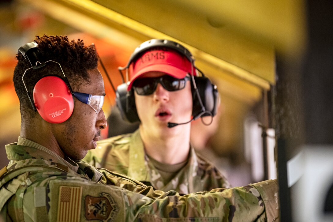 U.S. Air Force Senior Airman Nathaniel Mitchell, right, 423rd Security Forces Squadron (SFS) combat arms training and maintenance instructor, gives instructions to Airman 1st Class Shawn Morris-Jackson, 423rd SFS armory patrolman, during a M18 handgun qualification course at RAF Molesworth, England, July 28, 2020. During the course, Airmen from the 423rd SFS became familiar with the M18 and learned about its various functions and overall benefits such as improved ergonomics, target acquisition, reliability and durability to increase shooter lethality. The M18 Sig Sauer Modular Handgun System will be replacing the M9 Beretta which has been in use for over 30 years. (U.S. Air Force photo by Senior Airman Eugene Oliver)