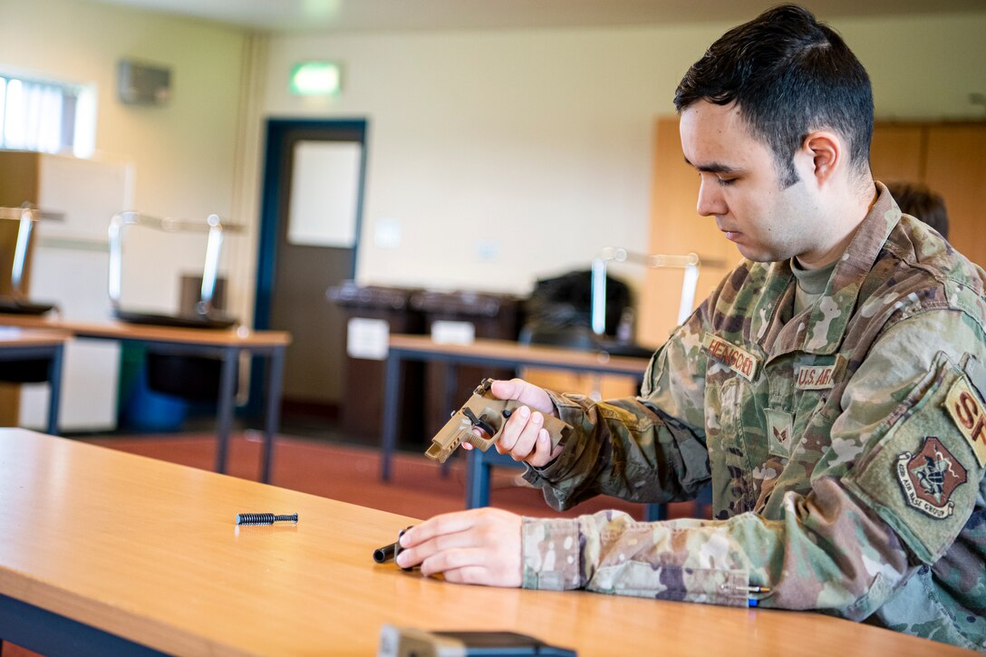 U.S. Air Force Senior Airman Jose Henscheid, 423rd Security Forces Squadron (SFS) emergency communications center controller, inspects a M18 handgun during a qualification course, at RAF Molesworth, England, July 28, 2020. During the course, Airmen from the 423rd SFS became familiar with the M18 and learned about its various functions and overall benefits such as improved ergonomics, target acquisition, reliability and durability to increase shooter lethality. The M18 Sig Sauer Modular Handgun System will be replacing the M9 Beretta which has been in use for over 30 years. (U.S. Air Force photo by Senior Airman Eugene Oliver)