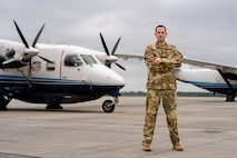 Airman stands in front of aircraft.