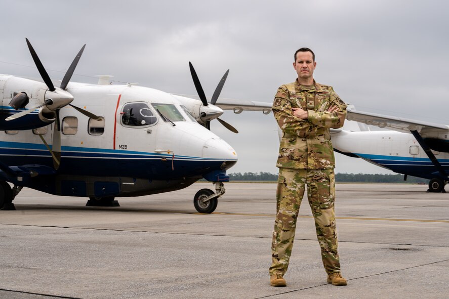 Airman stands in front of aircraft.
