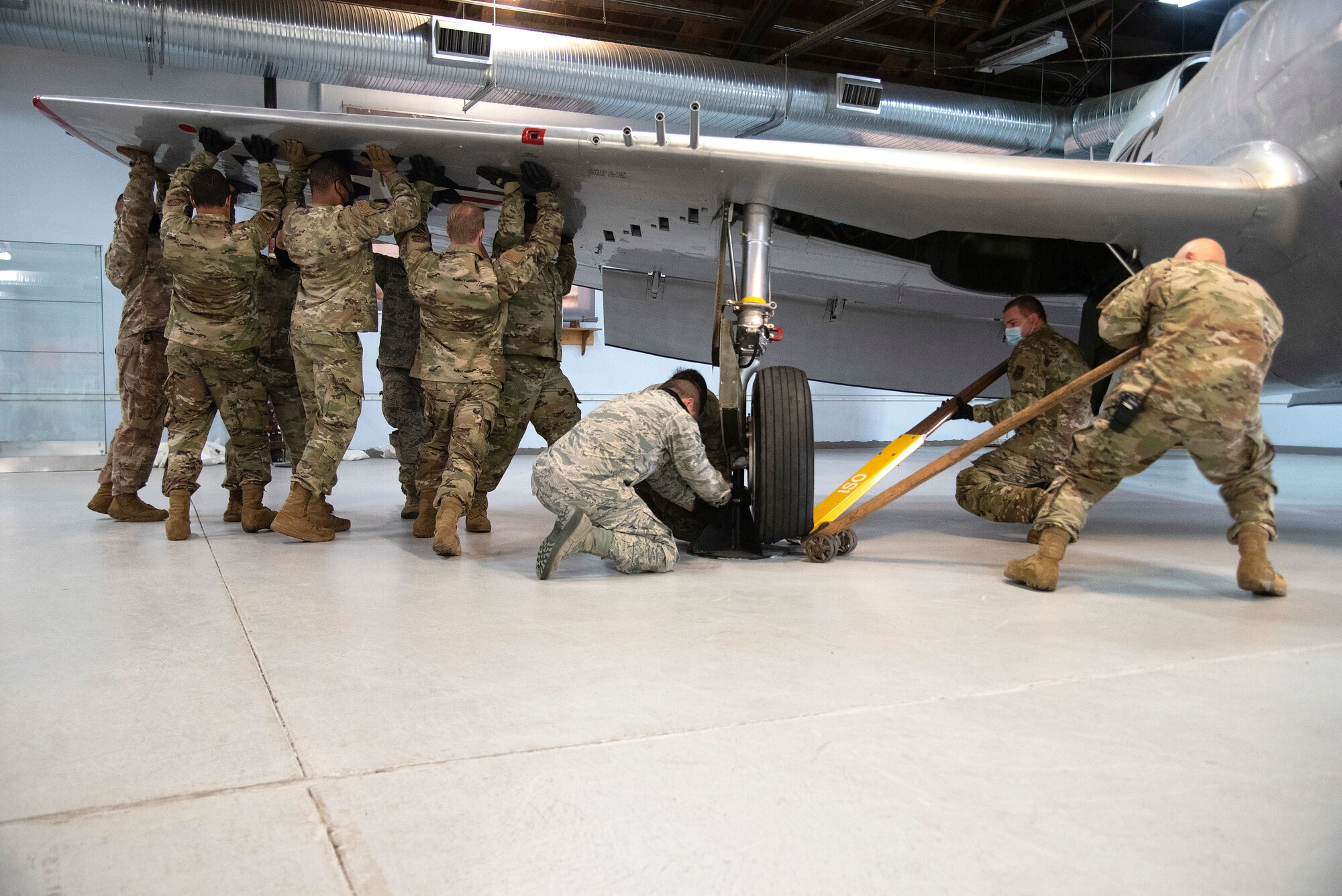 Photo of Airmen lifting up wing of aircraft