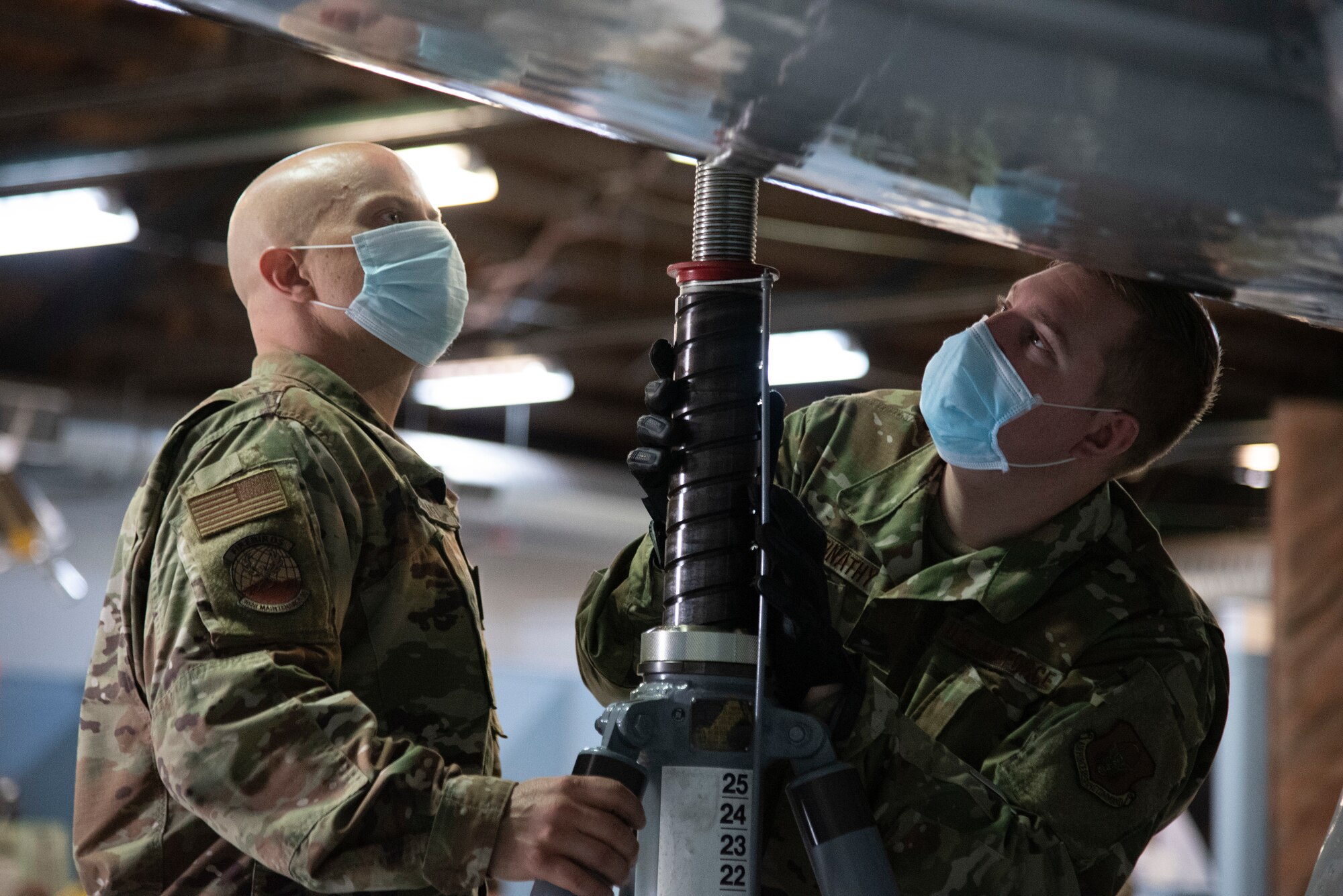 Photo of Airmen making sure tripod jack is in place under aircraft wing