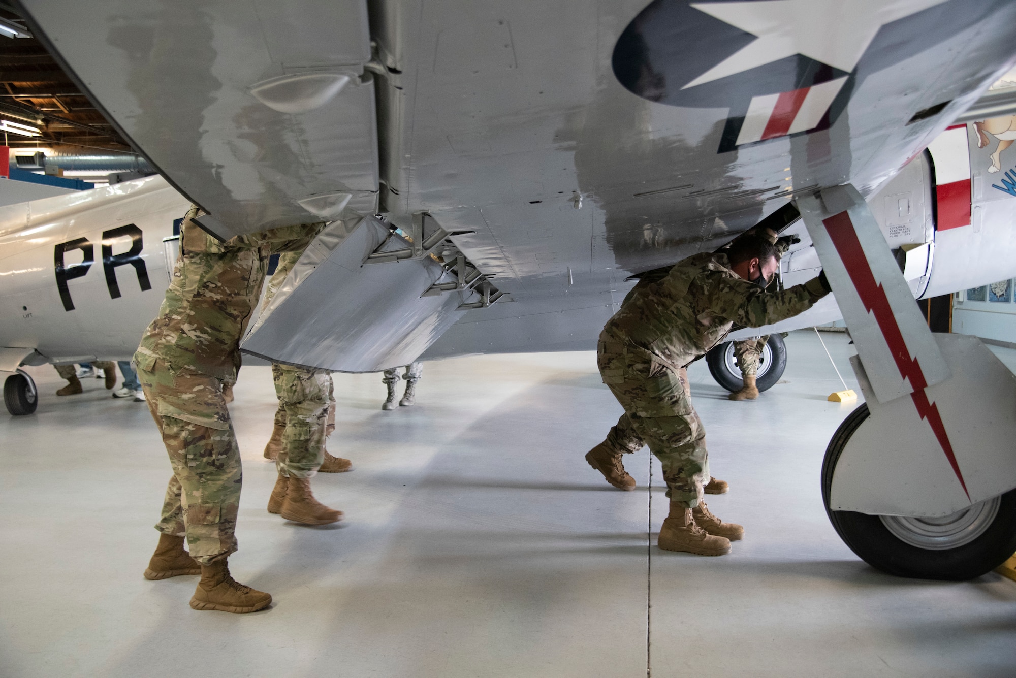 Photo of Airmen pushing along wing of aircraft
