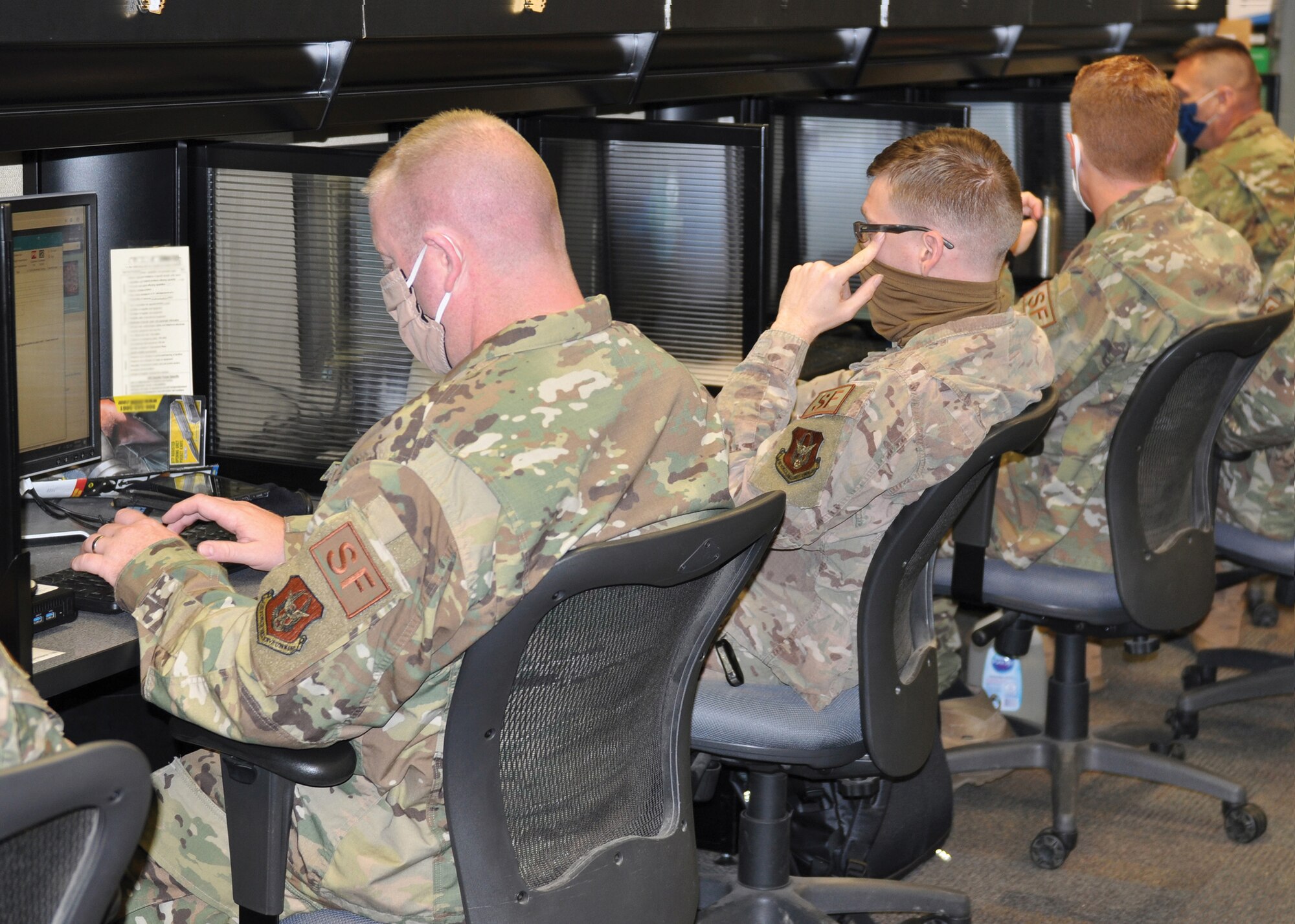 Master Sgt. Kevin Kelly (far left) and Staff Sgt. Mitchiner Underhill and other members of the 445th Security Forces Squadron, work to complete required readiness training in the 445th SFS computer lab, despite new challenges associated with the COVID-19 pandemic. To protect themselves and others, members of the squadron wore masks and sanitized high-touch areas throughout the day, in addition to sanitizing communal work stations, like these, before and after each use. (U.S. Air Force photo by 1st Lt. Rachel Ingram)