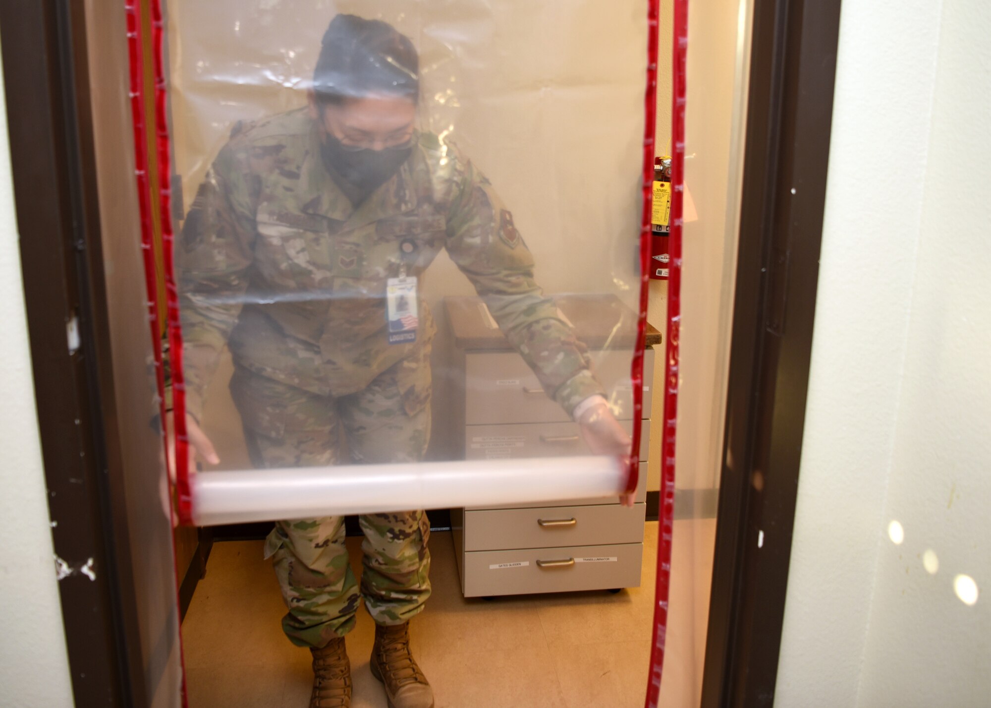 U.S. Air Force Staff Sgt. Sydney Raqueno, 17th Operations Medical Readiness Squadron, dental logistics NCO in charge, pulls down a plastic doorway barrier at the Ross Clinic’s dental facility, on Goodfellow Air Force Base, Texas, Aug. 5, 2020.  Raqueno led a team of Airmen to install the COVID-19 prevention upgrade barriers and completed the task in one duty day. (U.S. Air Force photo by Airman 1st Class Abbey Rieves)