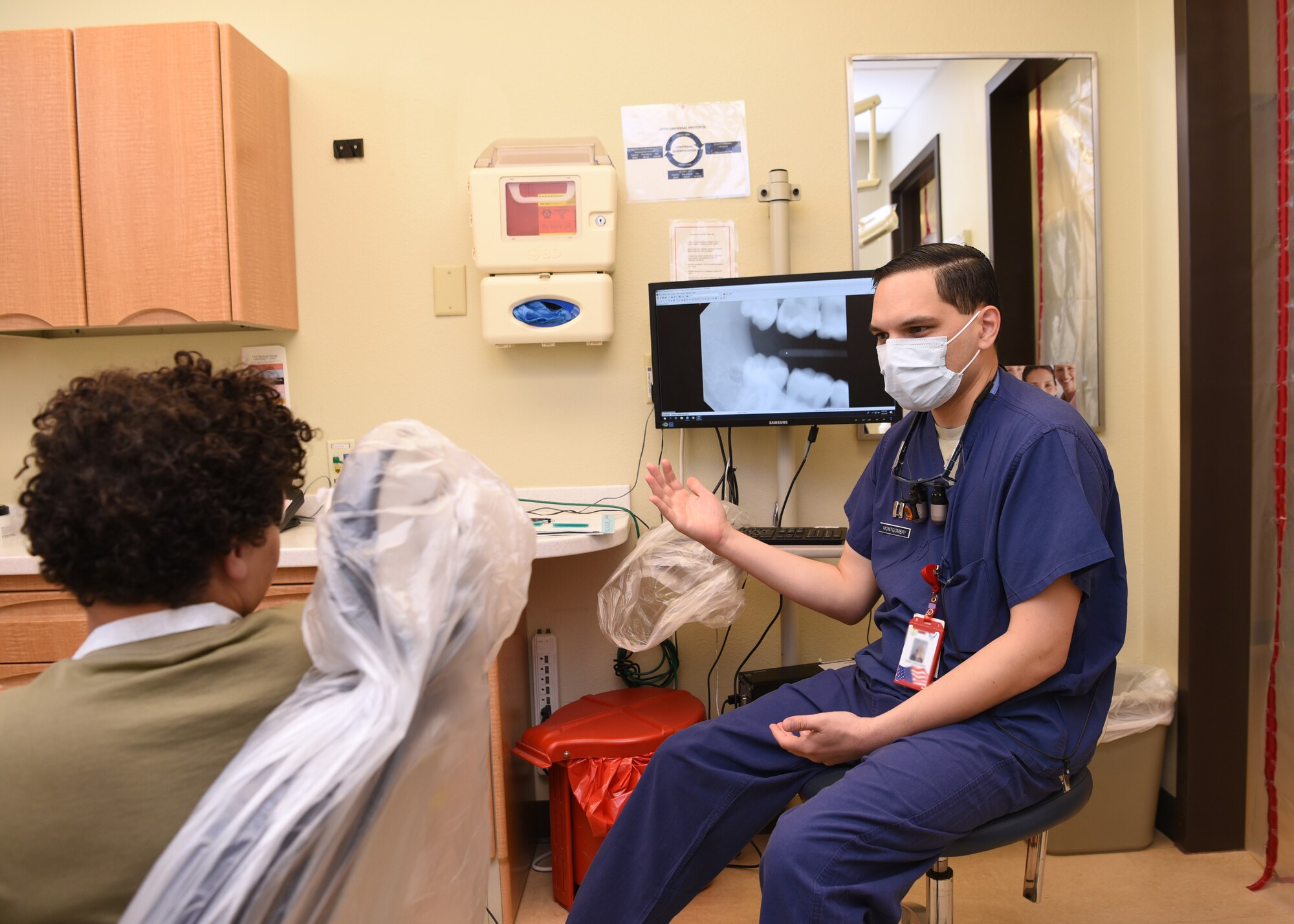 U.S. Air Force Capt. Thomas Montgomery, 17th Medical Group general dentist, discusses an oral care plan with a patient at the Ross Clinic’s dental facility, on Goodfellow Air Force Base, Texas, Aug. 5, 2020. The room was sanitized before and after the patient was seen by the provider. (U.S. Air Force photo by Airman 1st Class Abbey Rieves)  Note: this photo has been edited to blur a medical badge.