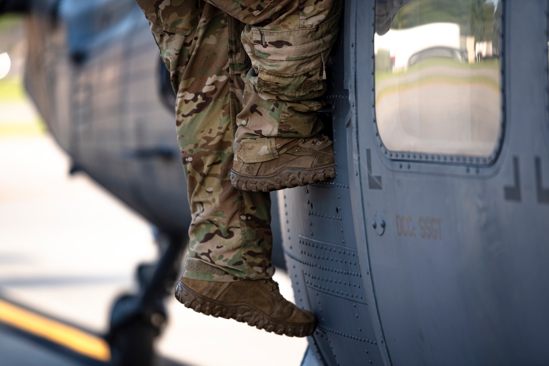 A photo of an Airman climbing down a helicopter before a flight
