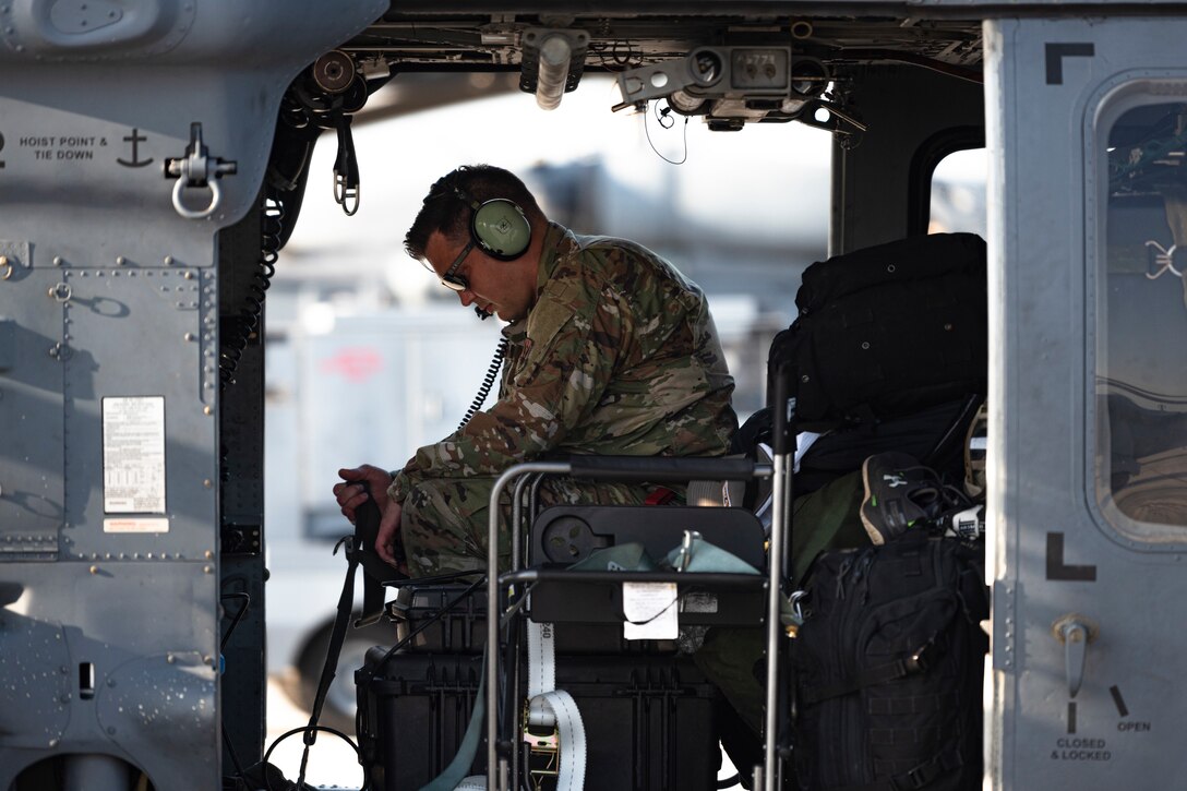 A photo of an Airman sitting in a helicopter before a flight