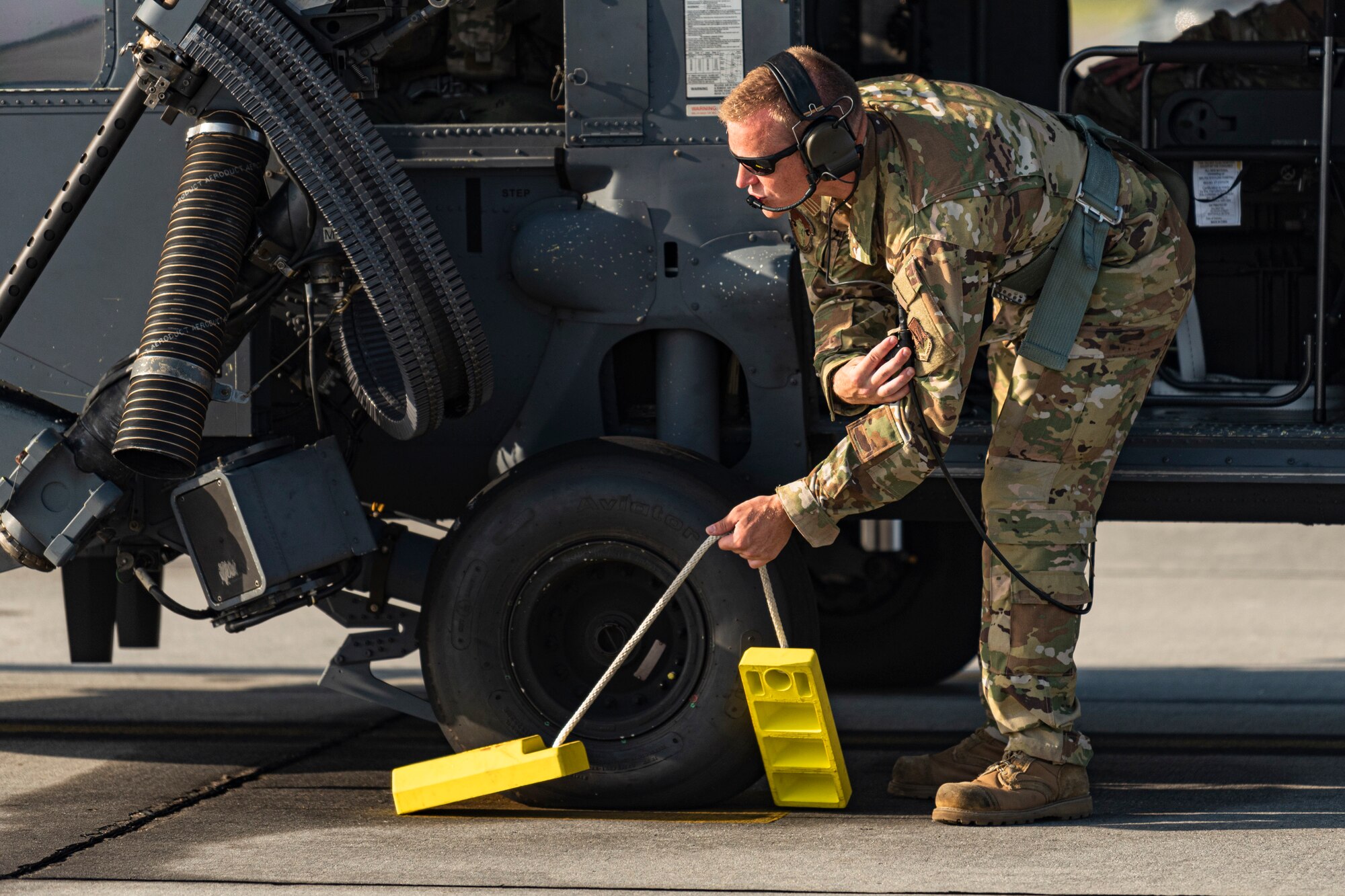 A photo of an Airman pulling wheel chocks before a flight
