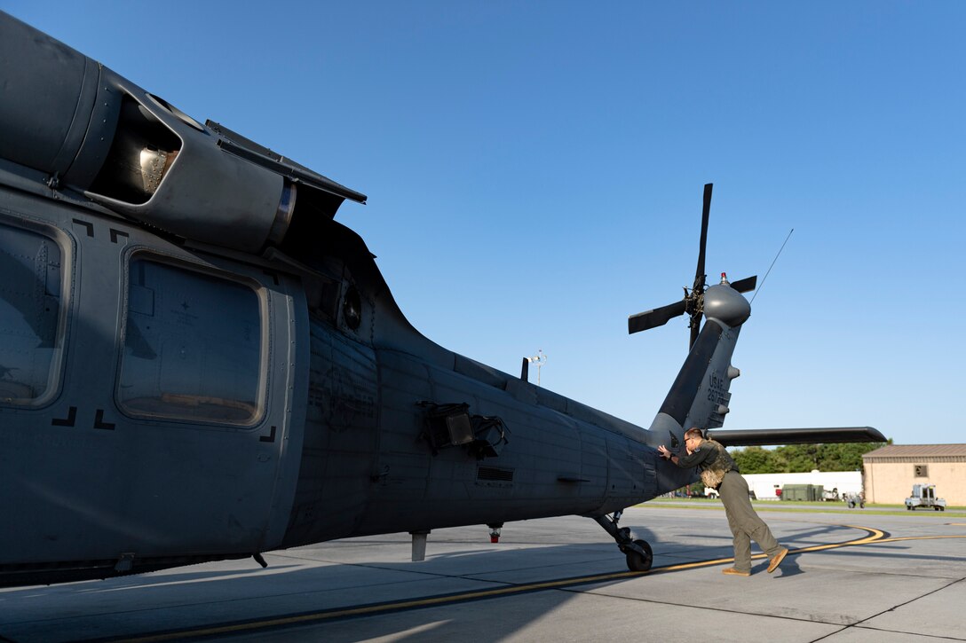 A photo of an Airman looking over a helicopter before a flight