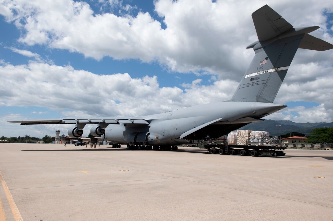 Airmen remove cargo from the back of a C-5B transport jet.