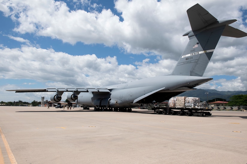 Airmen remove cargo from the back of a C-5B transport jet.