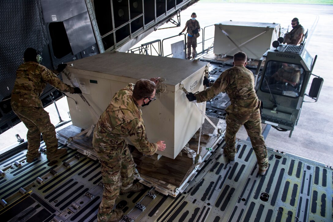 Airmen wearing face masks unload cargo during Exercise Swamp Devil