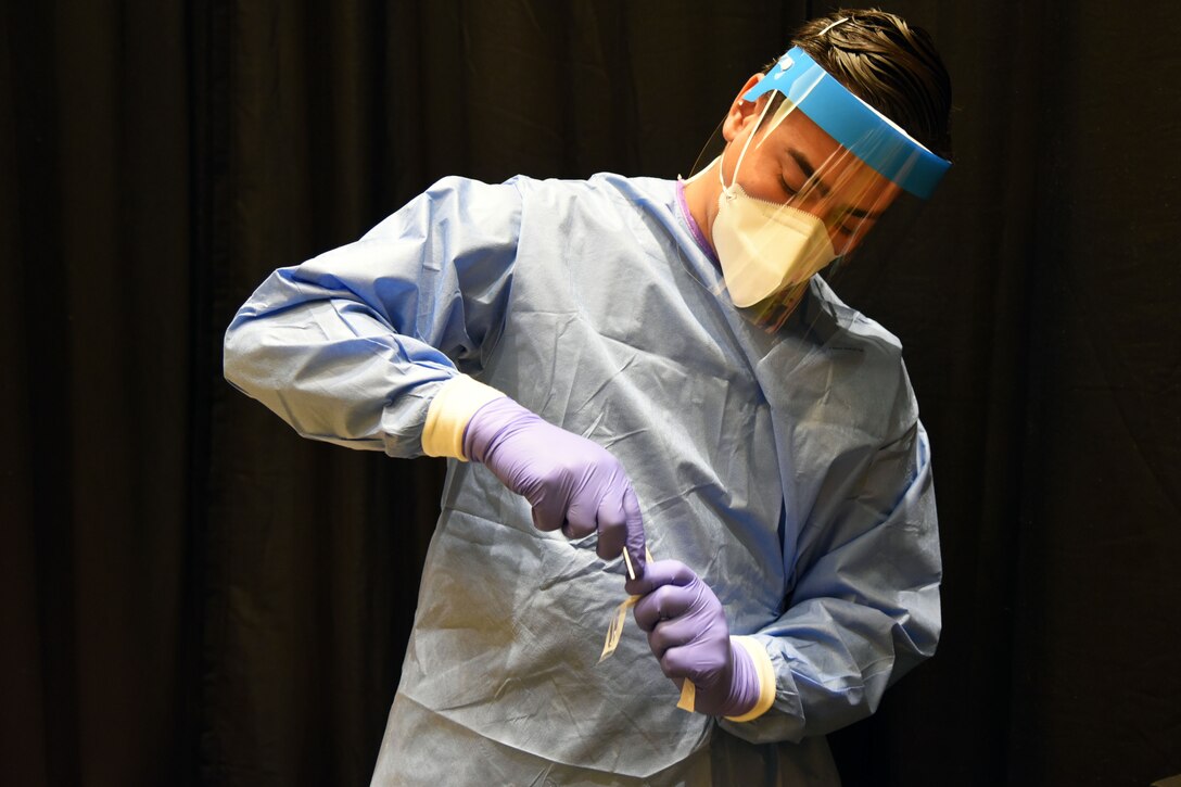 A guardsman wearing personal protective equipment prepares and collect COVID-19 test samples.