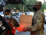 Sgt. Thalia Santos from Yonkers, N.Y., left, and Spc. Kirt Joseph from Brentwood, N.Y., members of the New York Army National Guard, load boxed, packaged food, into a vehicle at a food distribution site in the Bronx, New York Aug. 5, 2020.