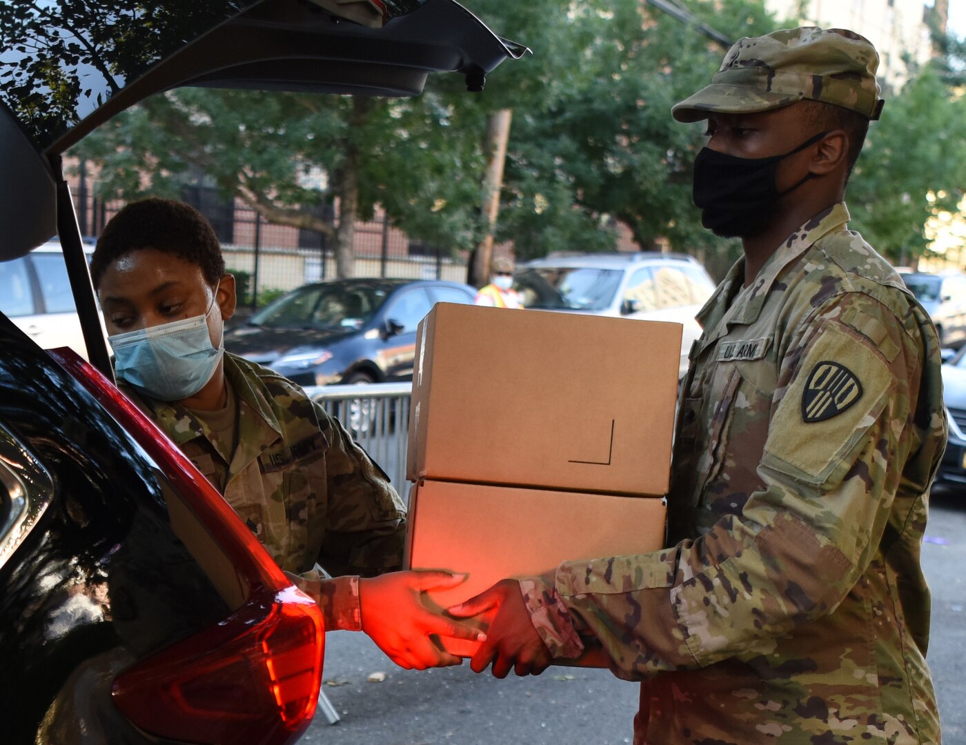 Sgt. Thalia Santos from Yonkers, N.Y., left, and Spc. Kirt Joseph from Brentwood, N.Y., members of the New York Army National Guard, load boxed, packaged food, into a vehicle at a food distribution site in the Bronx, New York Aug. 5, 2020.