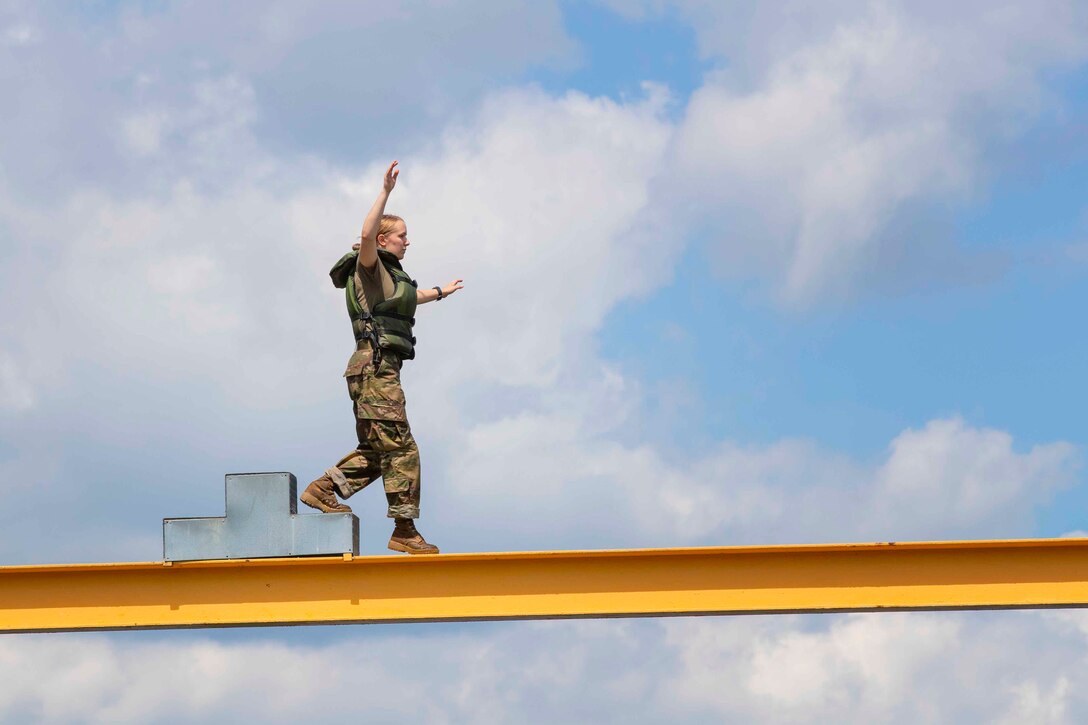 An Army cadet walks along a beam.