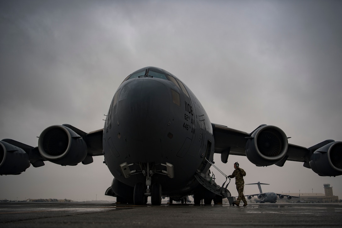 A service member approaches the staircase attached to a large military aircraft.