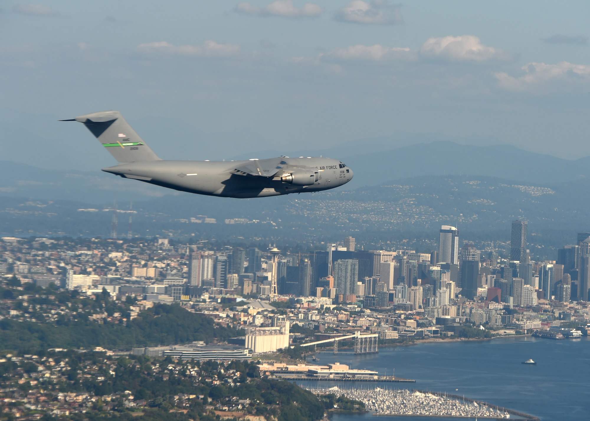 A C-17 Globemaster III from Joint Base Lewis-McChord flies over the Seattle skyline after completing a low-level formation training exercise in central Washington, Aug. 5, 2020. Flying in a formation of two or more aircrafts in a combat scenario allows for tactical advantage by establishing mutual support and mass of aircraft over an objective area.  (U.S. Air Force photo by Airman 1st Class Mikayla Heineck)