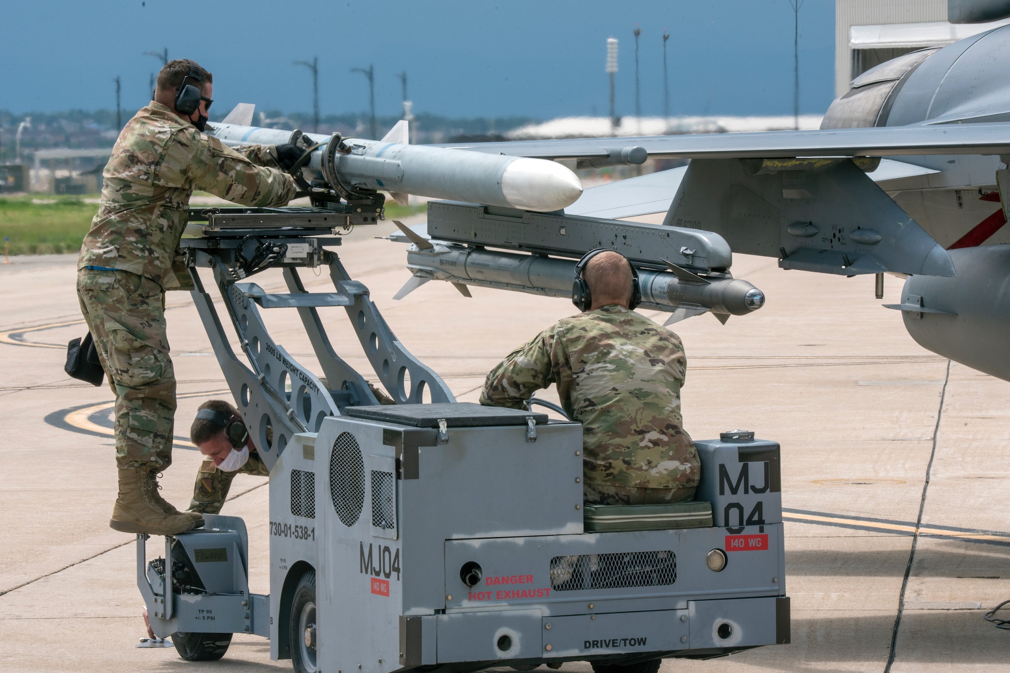 2 Airmen loading a missile on the wing of an F-16