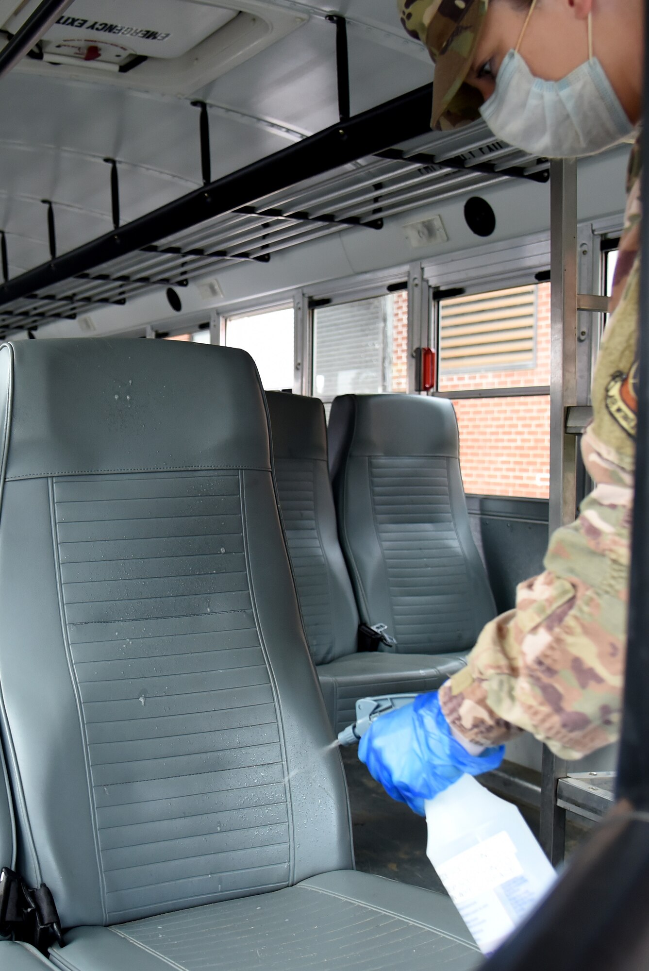 Photo of Airman sanitizing bus seats