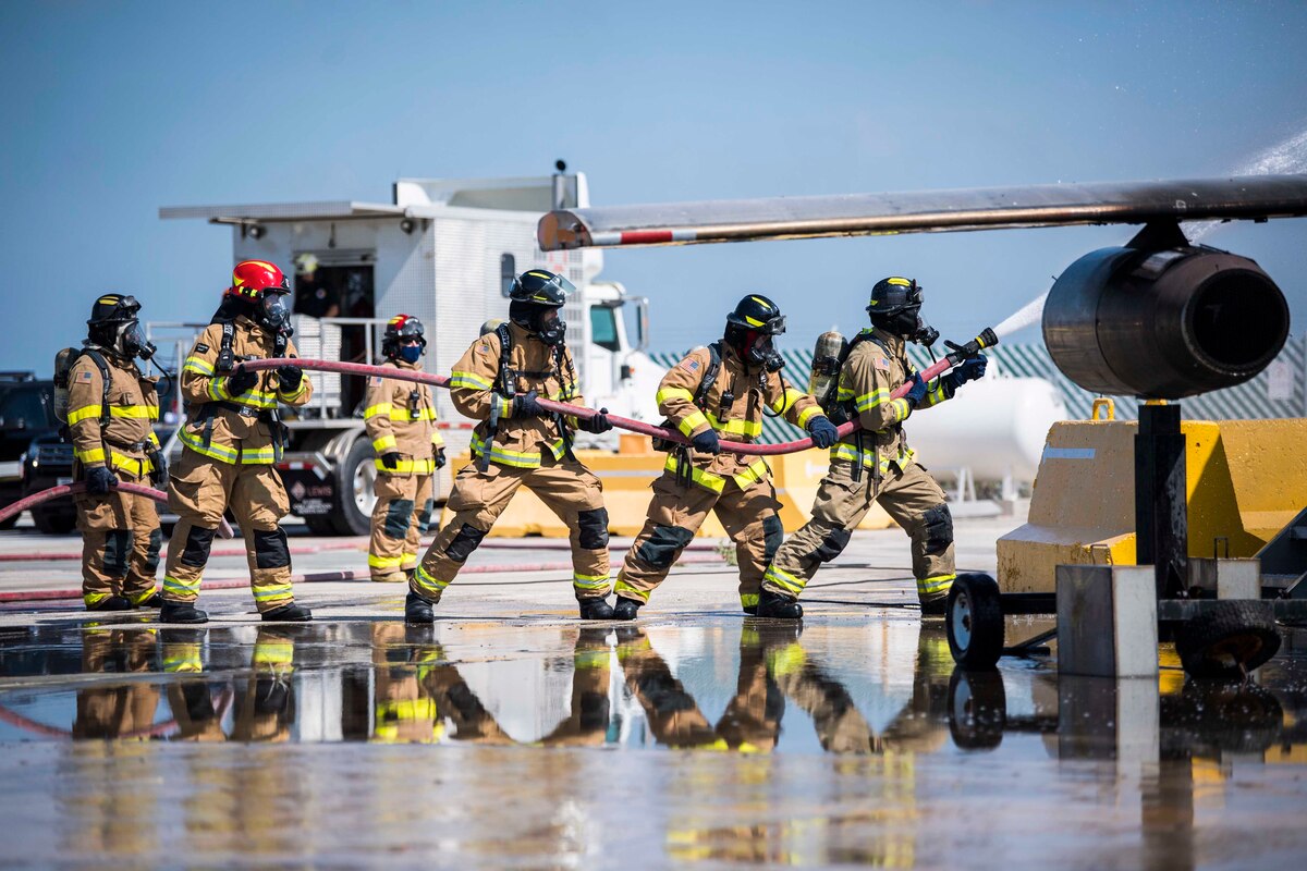 A group of sailors and firefighters battle an aircraft fire.