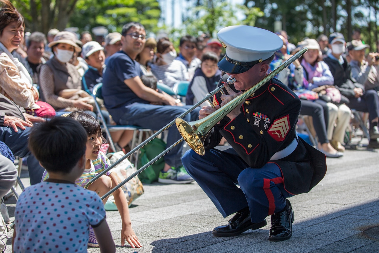 A Marine plays a trombone for an audience.