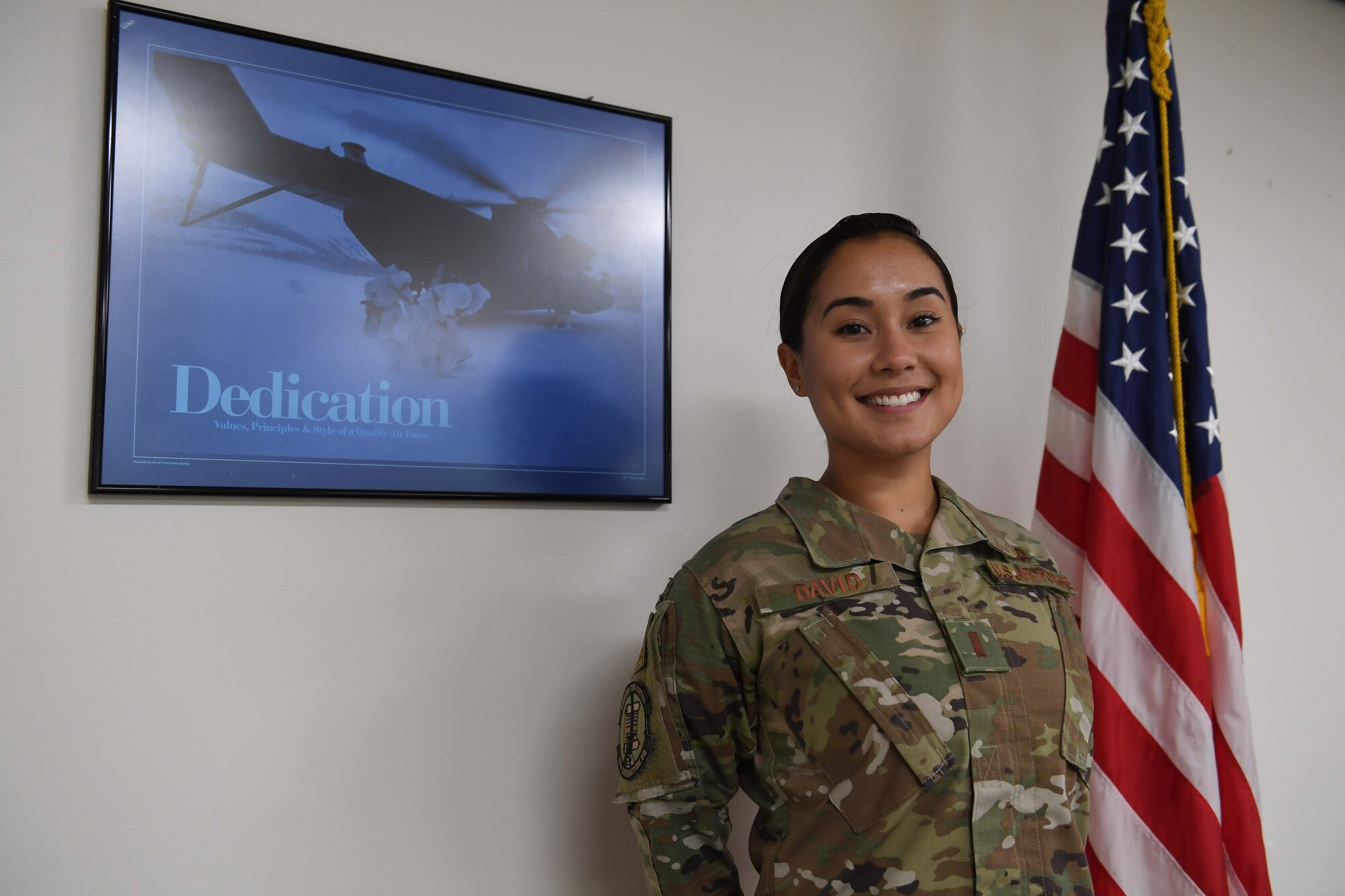 A woman stands in uniform in front of a flag