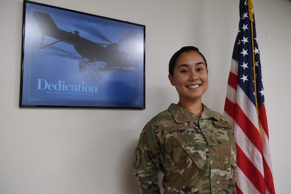 A woman stands in uniform in front of a flag