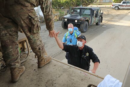 Pvt. Scott Green, a Soldier assigned to the 878th Engineer Vertical Construction Company, 105th Engineer Battalion, helps transport first responders over washed-out roads after Hurricane Isaias made landfall on Oak Island, North Carolina, Aug. 5, 2020.