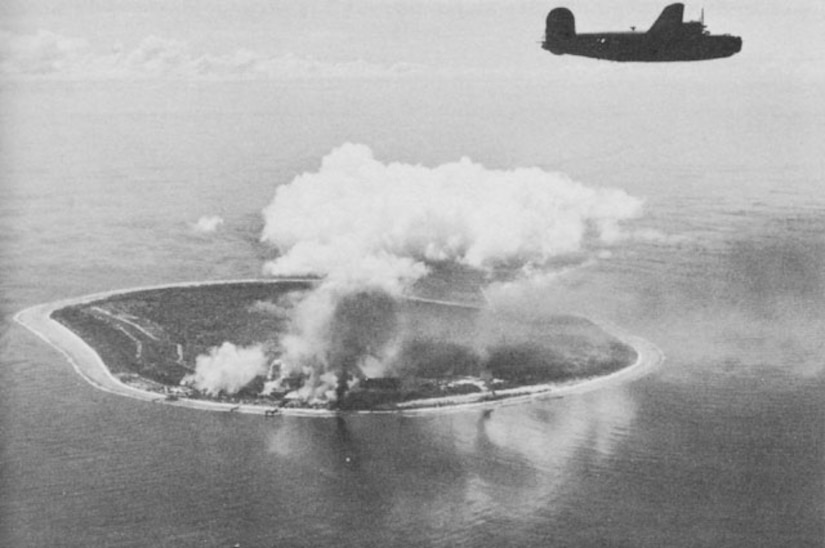 An aircraft flies over an island with smoke plume below.