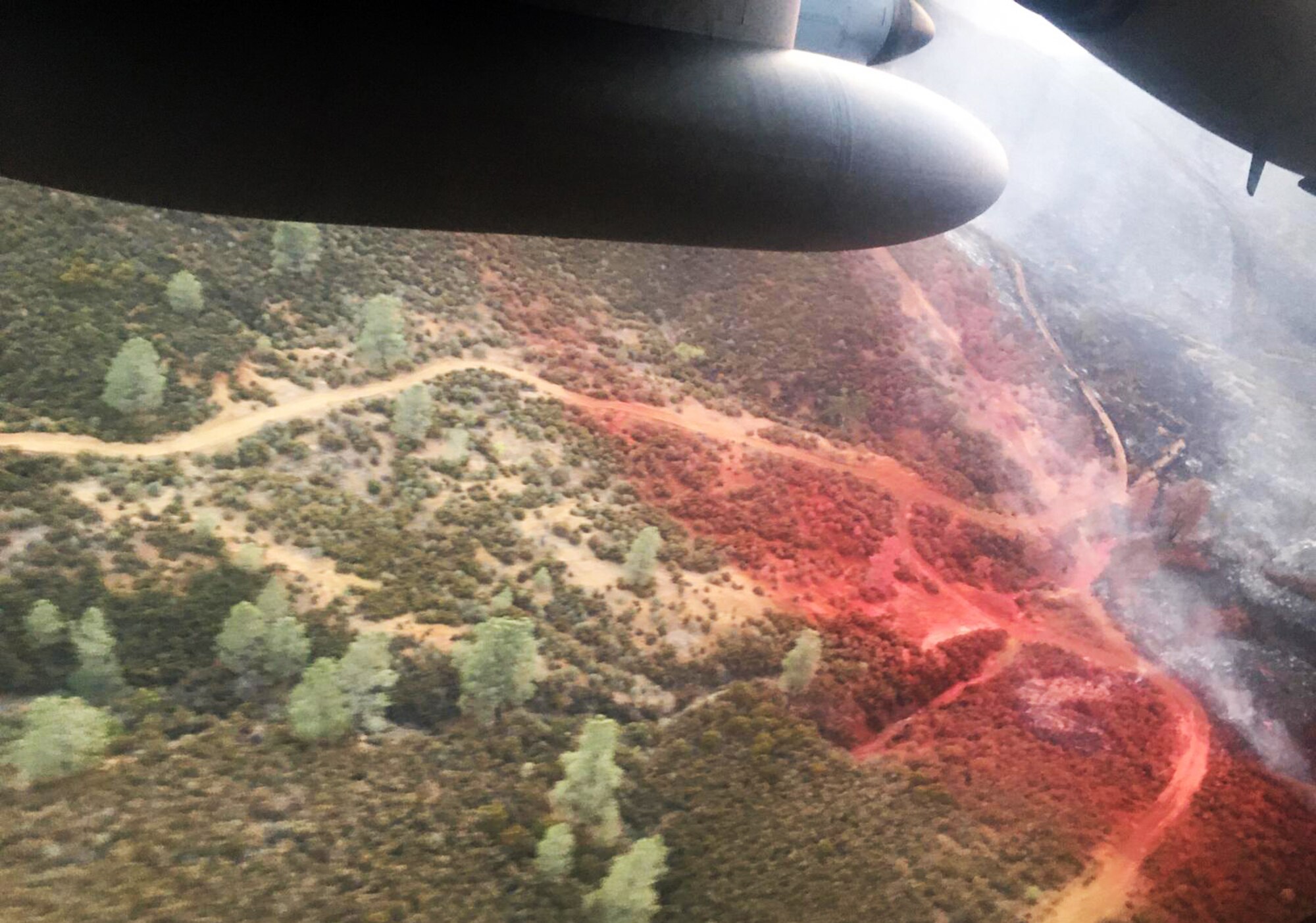 Large military aircraft flies over fires in California.