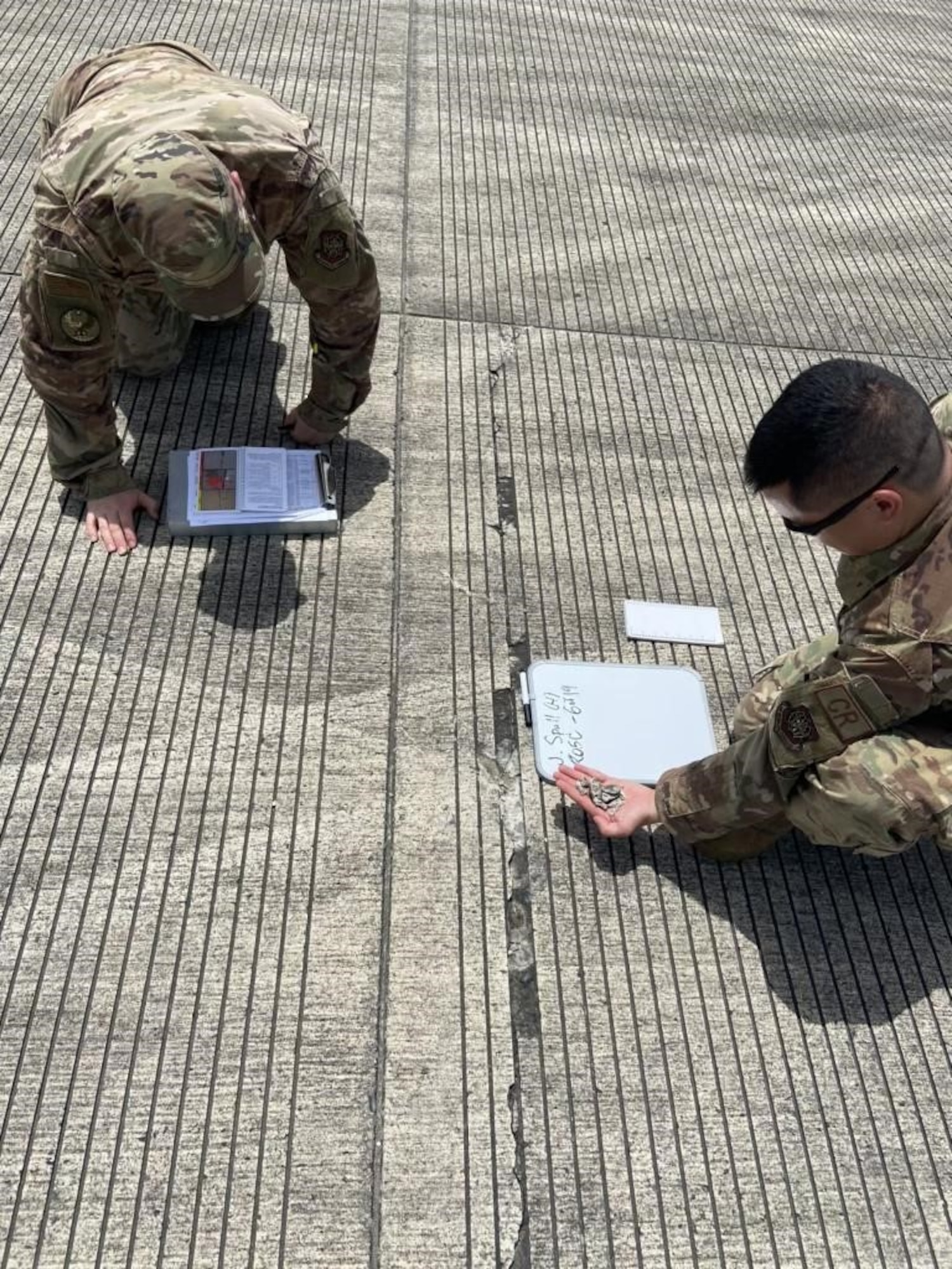 Tech. Sgt. Christopher Anderson, left, 621st Contingency Response Support Squadron engineering assistant, and Capt. Glenn Grecia, right, 621st Contingency Response Squadron civil engineer, inspect pavement distress to calculate the pavement condition index at Houma-Terrebonne Airport, Louisiana, July 11, 2020. The pavement condition index determines where it is safe to operate medium and heavy load aircraft. (U.S. Air Force photo by Tech. Sgt. Luther Mitchell Jr)