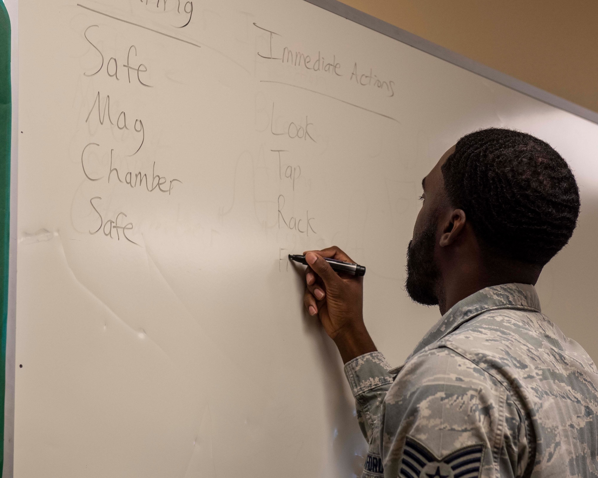 A male instructor writes with a marker on a dry erase board