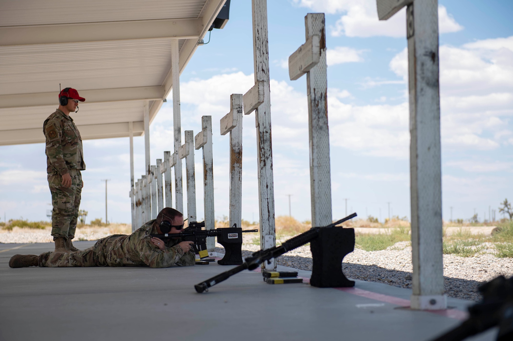 A CATM instructor observes as a male student fires an M4 carbine