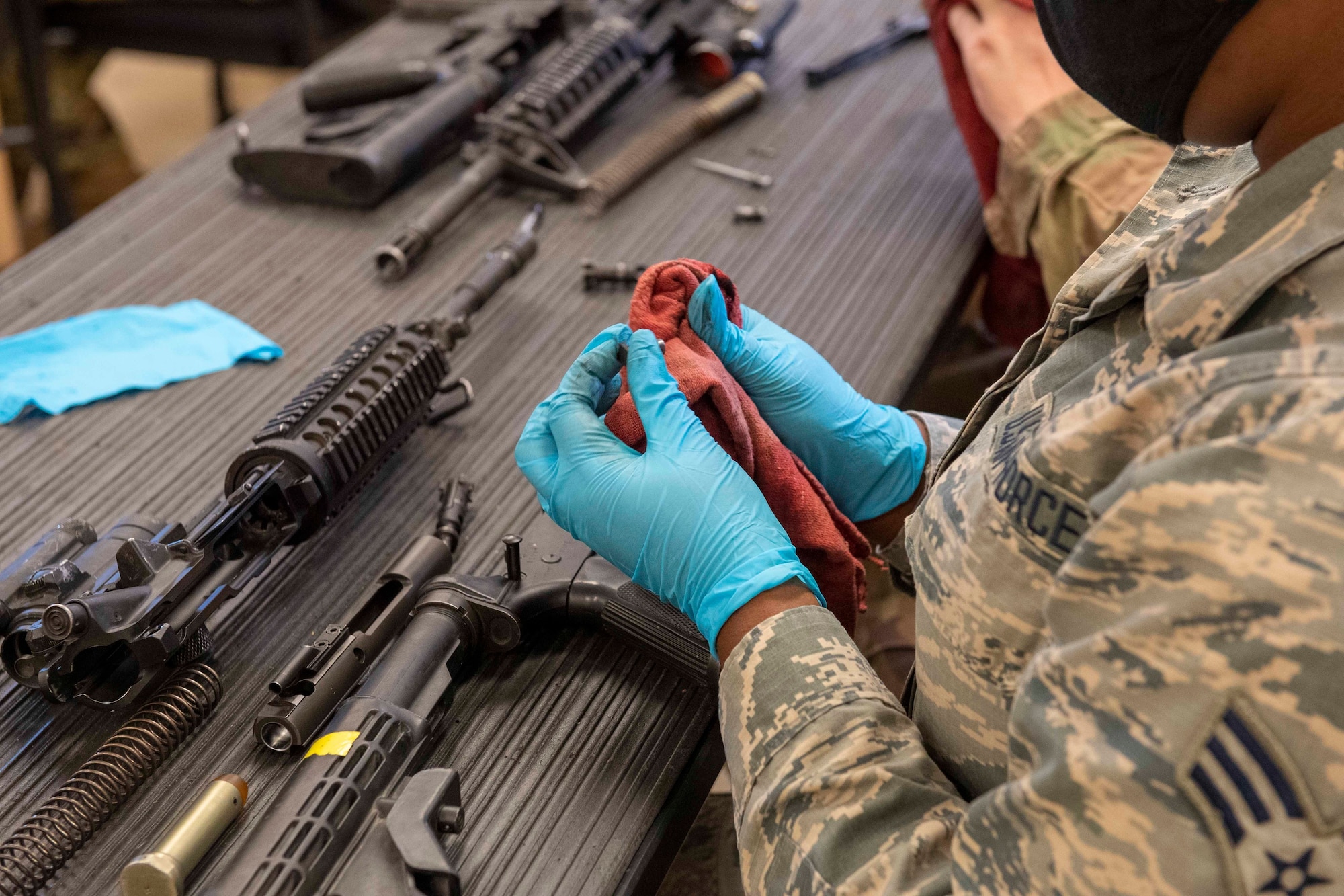 A female Airman disassembles and cleans an M4 carbine.