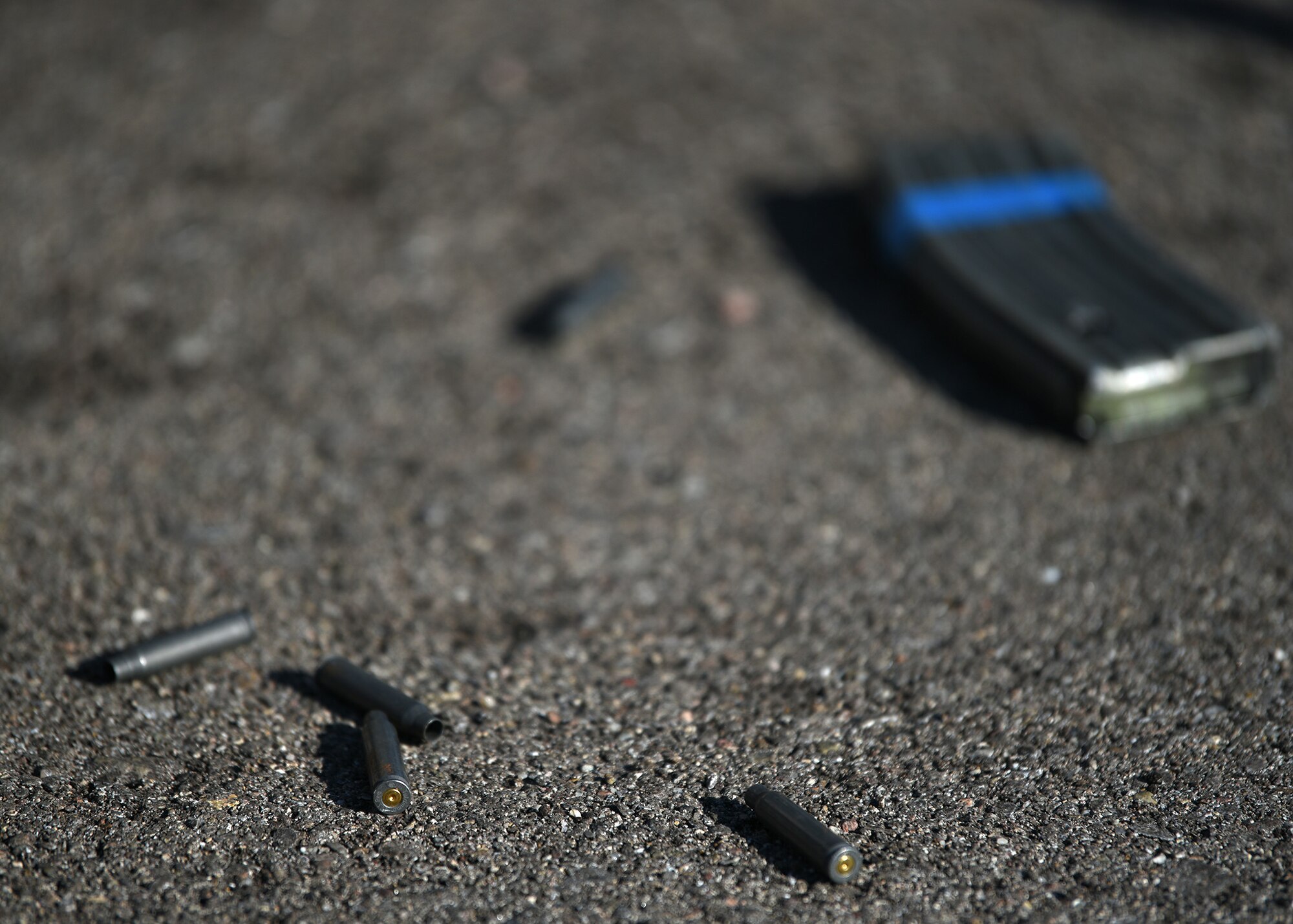 A photo of blank rounds of ammunition with a gun magazine laying on road