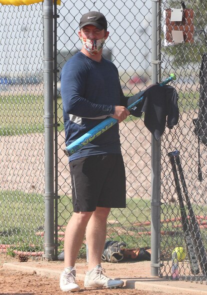 Thomas Taylor, Distributed Mission Operations Centers for Space, uses a rag to sanitize a bat while watching gameplay Aug. 4, 2020 at Schriever Air Force Base, Colorado. Players could not use the same baseball bat in back-to-back at-bats and had to clean equipment various times throughout the contest. (U.S. Air Force photo by Marcus Hill.