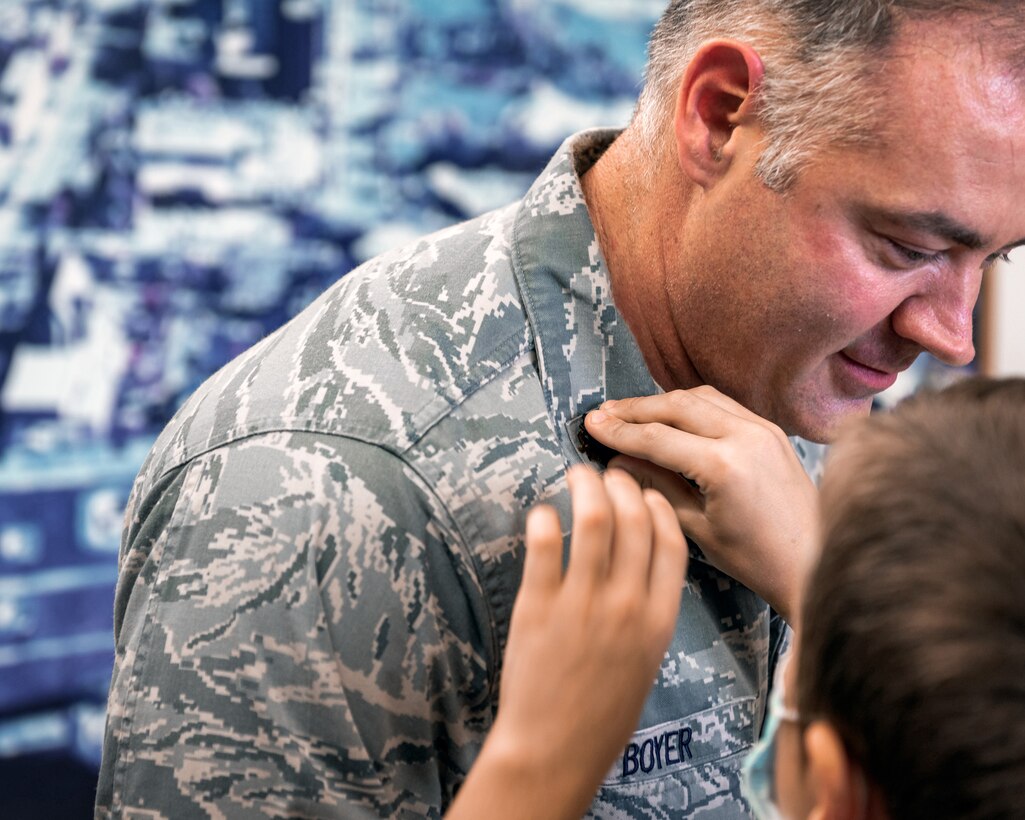 Children pinning rank insignia on man.