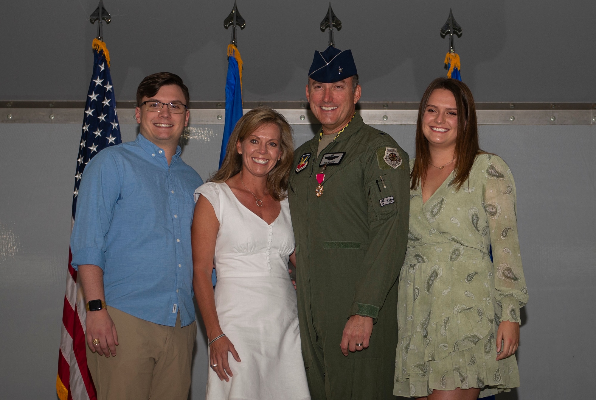 Brig. Gen. Robert Novotny smiles at the camera while surrounded by his wife and two children on stage during a ceremony.