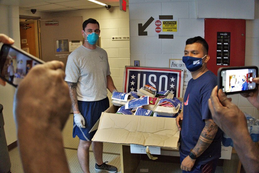 Airmen stand next to a donated box of food.