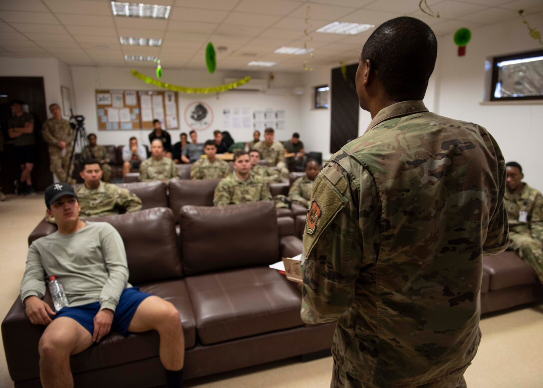 Soldiers sitting and listening to a speech given by another military member